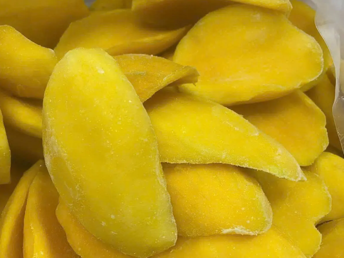 Close-up of frost-covered frozen mango cheeks showing the flesh grain.