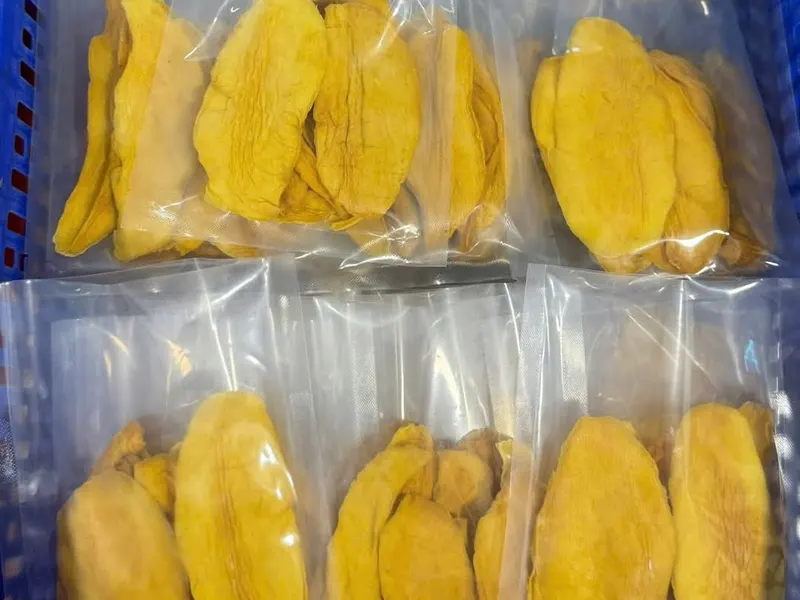 Vacuum-sealed packs of dried mango stacked in a green crate.
