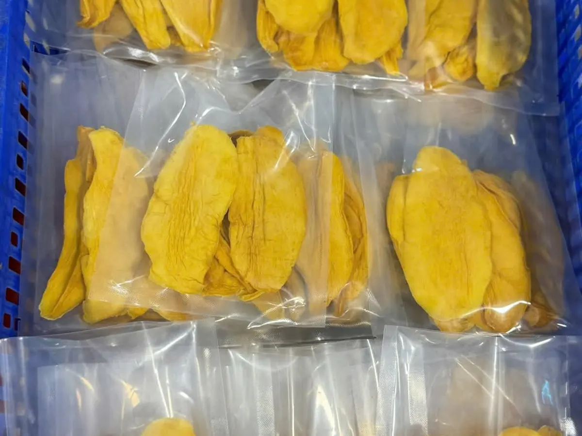 Clear vacuum packs of dried mango stacked inside a blue plastic crate.