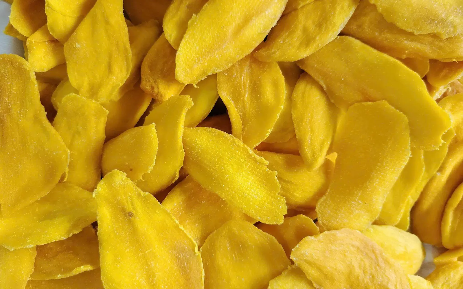 Full-frame close-up of golden soft-dried mango slices.