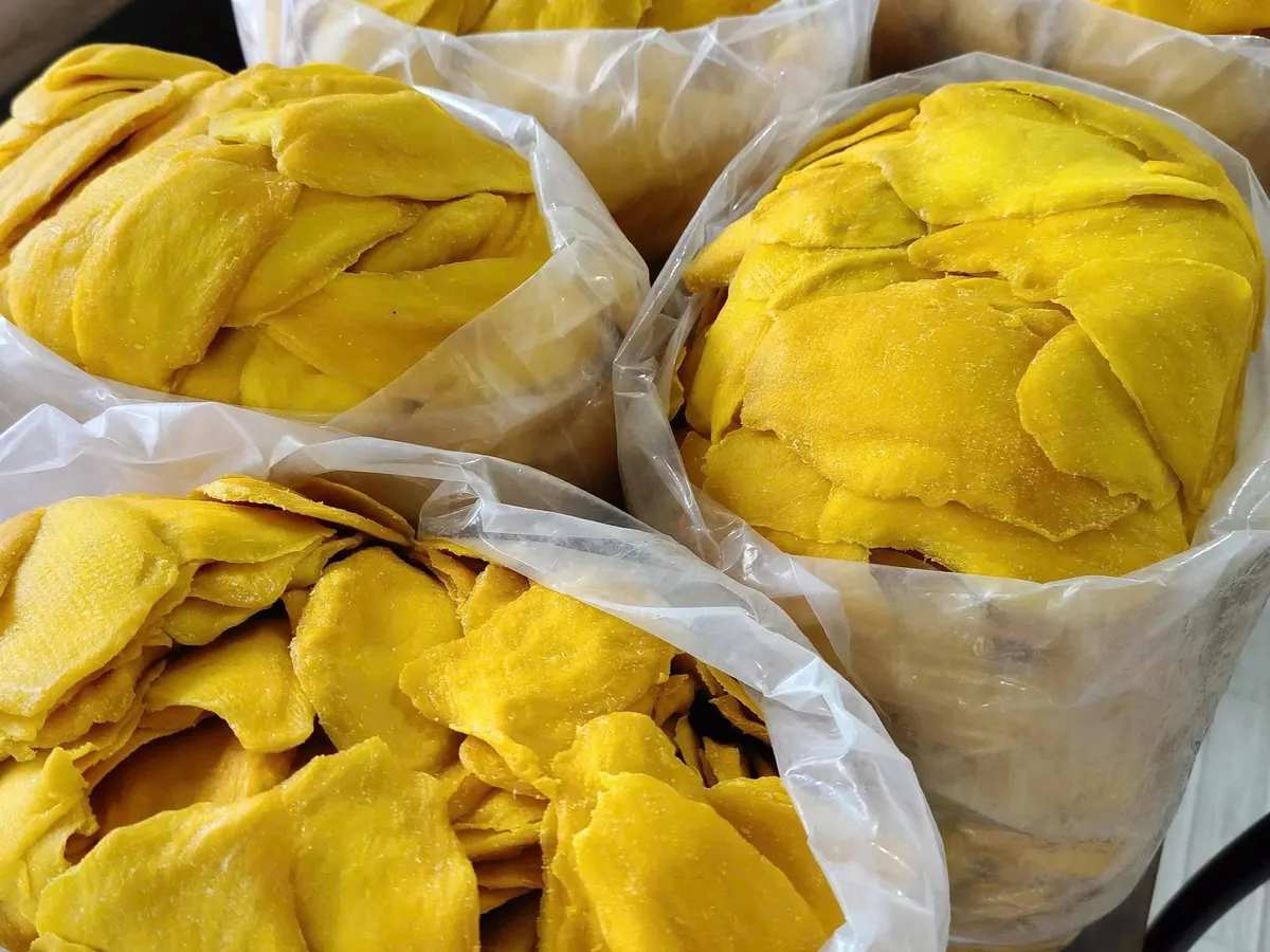 Several open white polybags packed with soft-dried mango side by side.