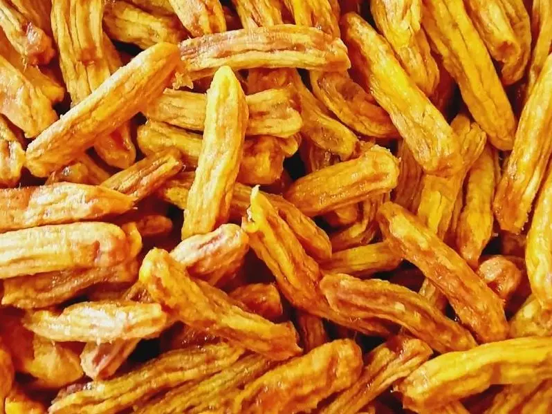 Full-frame close-up of deep amber soft-dried banana pieces.