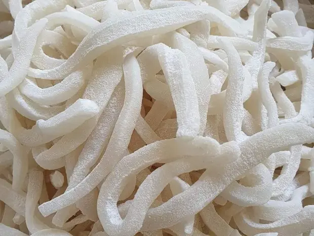 Full-frame close-up of curled ivory-white dried coconut ribbons.