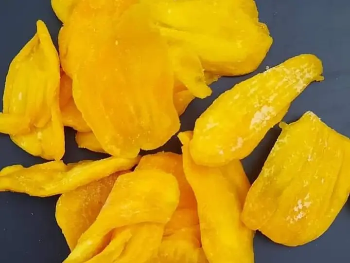 Soft-dried jackfruit slices scattered on a dark background.