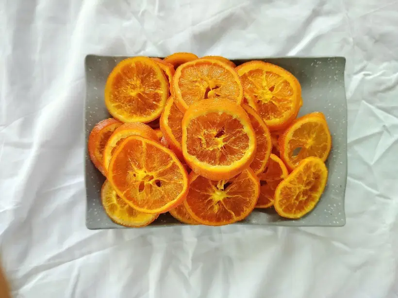 Top-down view of soft-dried orange slices filling a grey stone tray.
