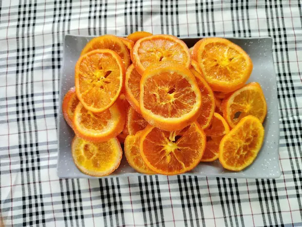 Grey stone tray of soft-dried orange slices on a black-and-white checked cloth.