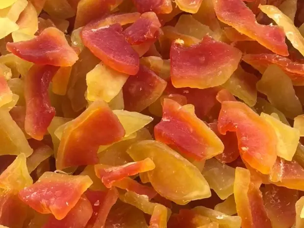 Close-up of bulk soft-dried papaya pieces in yellow and red tones.
