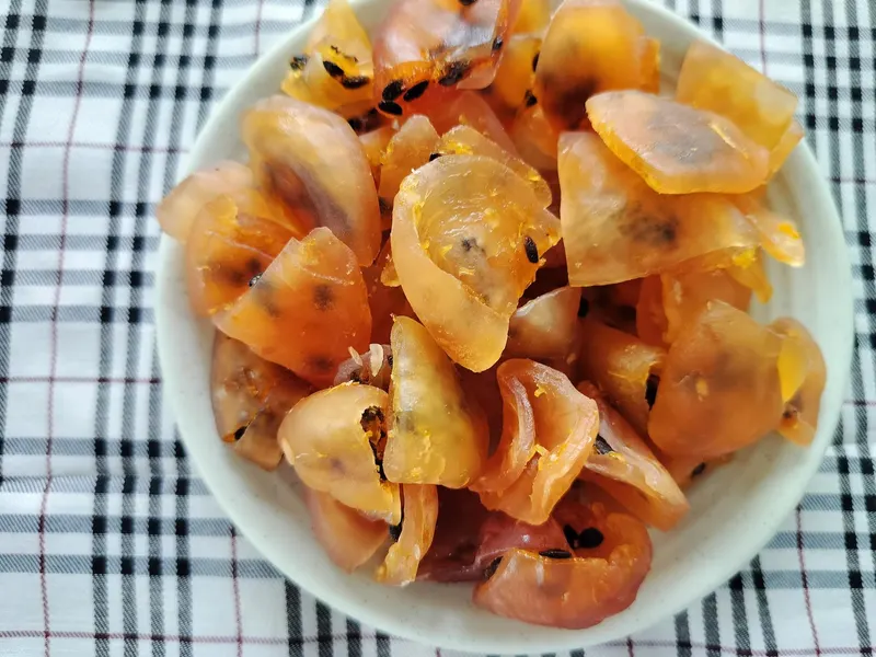 Close-up bowl of soft-dried passion fruit pieces on a checked cloth