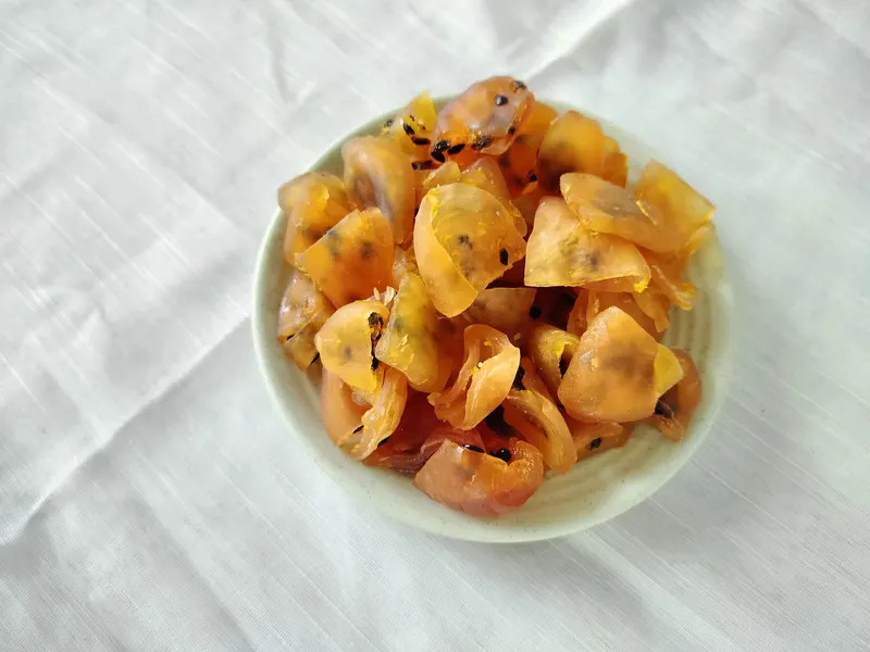Top-down view of a pale bowl of soft-dried passion fruit on white cloth