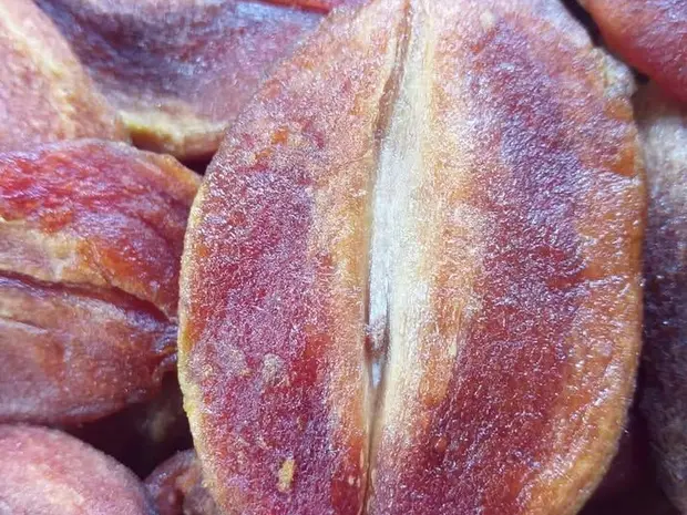 Close-up of purple-brown soft-dried sapodilla slices with a sugar bloom.